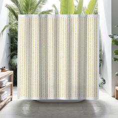 a shower curtain with white and yellow dots on it in a bathroom next to potted plants