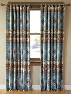 a window with blue and brown curtains hanging on the side of it in front of a wooden floor