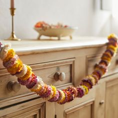 a garland is hanging from the side of a dresser in front of a bowl and candle