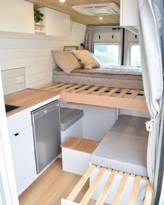 the interior of a camper with white walls and wood flooring, built - in storage