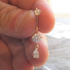 a person is holding an earring in their left hand and the other side has a diamond dangling from it