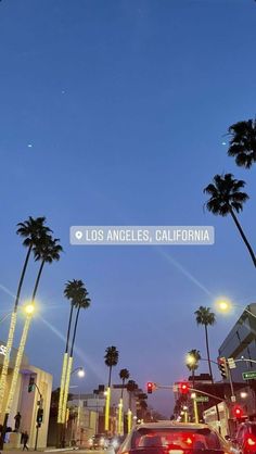 cars driving down the street at night with palm trees in the foreground and los angeles, california sign above