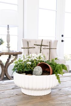 a white planter filled with plants on top of a wooden table