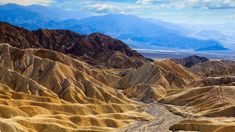 the mountains are covered in yellow and brown sand, with a river running through them