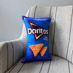 a pillow that is sitting on a chair with some chips in it and the words doritos written on it