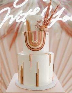 a three tiered white cake sitting on top of a table next to a neon sign