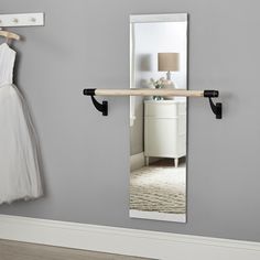 a dress hanging on a rail in front of a mirror with a coat hanger next to it