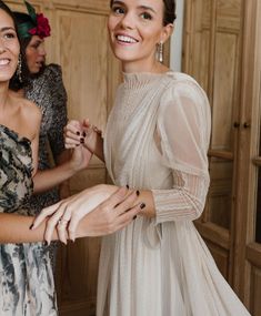 two women standing next to each other in front of wooden closets holding onto one another's hands