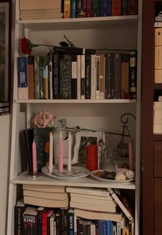 a book shelf filled with books and candles