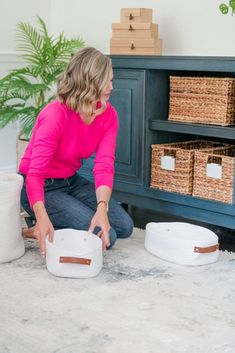 a woman kneeling down on the floor with some baskets