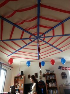 a woman sitting on a couch in front of a book shelf with red, white and blue streamers hanging from the ceiling