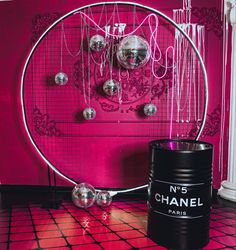 a pink room with chandelier and metal balls hanging from the ceiling, next to a black barrel