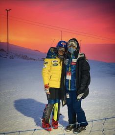 two people standing next to each other in the snow