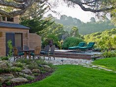 a backyard with green grass, rocks and trees