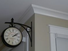 a clock hanging from the side of a wall next to a doorway and door way