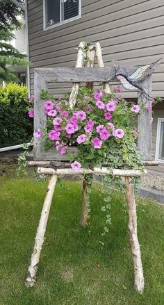 an old chair with flowers growing out of it in front of a house on the grass