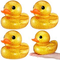 four yellow rubber ducks with black eyes and orange beaks, in front of a white background