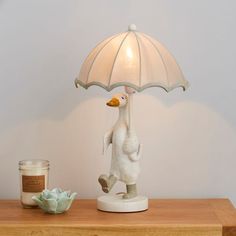 a ducky lamp with an umbrella on top of a table next to a candle