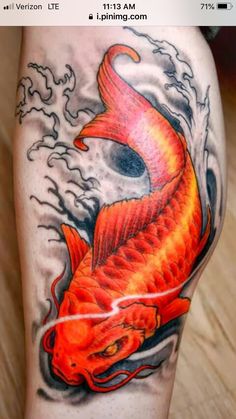 an orange fish tattoo on the leg with water splashing around it's head