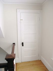 an empty room with a white door and wooden stairs