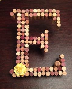 the letter f made out of wine corks on a table with a yellow flower