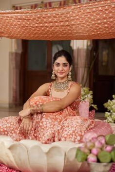 a woman in an orange and white dress sitting on a flower covered floor with flowers around her