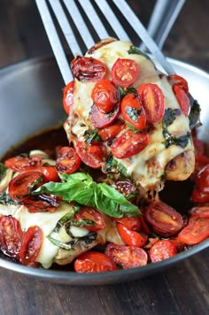 a bowl filled with meat covered in tomatoes and sauce on top of a wooden table