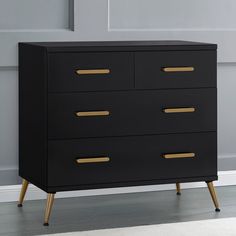 a black chest of drawers with gold handles in front of a white wall and floor