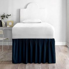 a white bed with blue ruffled bedskirt