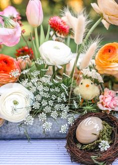 an arrangement of flowers and birds nest on a table