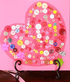 a pink card with buttons on it and a heart shaped pin board in the middle