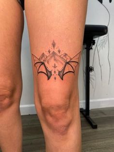 a woman's leg with a bat tattoo on the side of her thigh,