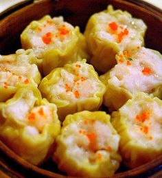 some dumplings are in a wooden bowl with orange sprinkles on them