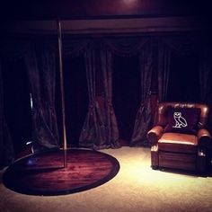 a living room with a chair and a pole on the floor in front of curtains