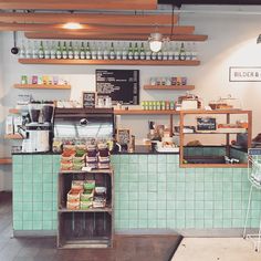 the interior of a coffee shop with green tiles and shelves filled with food, drinks, and other items