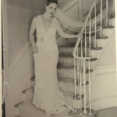 an old photo of a woman in a wedding dress standing on the stairs with her veil over her head