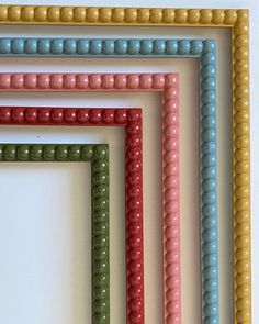 four different colored beaded frames on a white wall