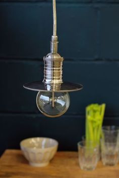 a light fixture hanging from the ceiling over a table with glasses and bowls on it