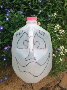 a white jug with a face drawn on it sitting in front of some blue flowers