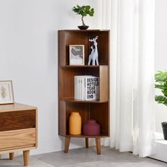 a wooden shelf with books and pictures on it in a living room next to a window