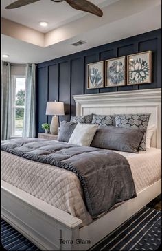 a bedroom with a bed, ceiling fan and two pictures on the wall above it