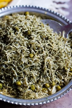 a metal bowl filled with rice and peas