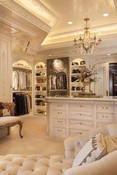 an elegant closet with white furniture and chandelier