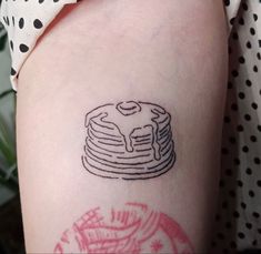 a woman's arm with a tattoo of a stack of pancakes on top of it