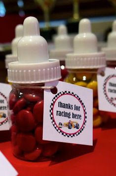 small jars filled with red and yellow candies sitting on top of a table next to each other