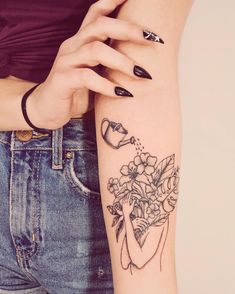 a woman's arm with flowers and a watering can tattoo on her left arm