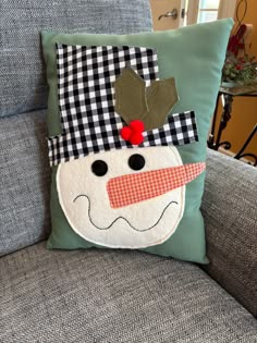 a snowman pillow sitting on top of a couch next to a blue sofa cushion