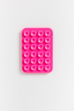 a close up of a pink object on a white surface with holes in the middle