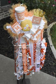 an orange and white decoration on top of a pole with fries, hotdogs and soda