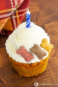 a cupcake with white frosting and two dogs on top is sitting on a wooden table